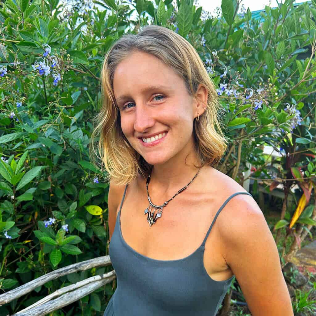 Leah smiling outdoors at Rainbow Bridge Hawaii, surrounded by tropical greenery.