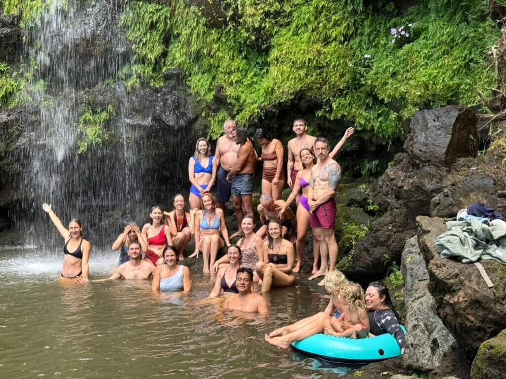 Lucid dream retreat participants swimming at a lush Hawaiian waterfall at Rainbow Bridge Hawaii, surrounded by tropical greenery