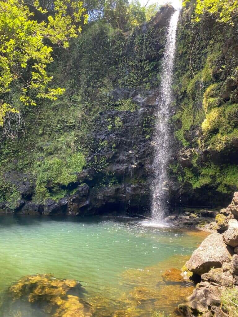 Waterfall flowing into a clear pool on the Rainbow Bridge Hawaii land.