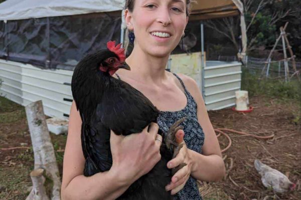 Woman holding a black hen at Rainbow Bridge Hawaii farm