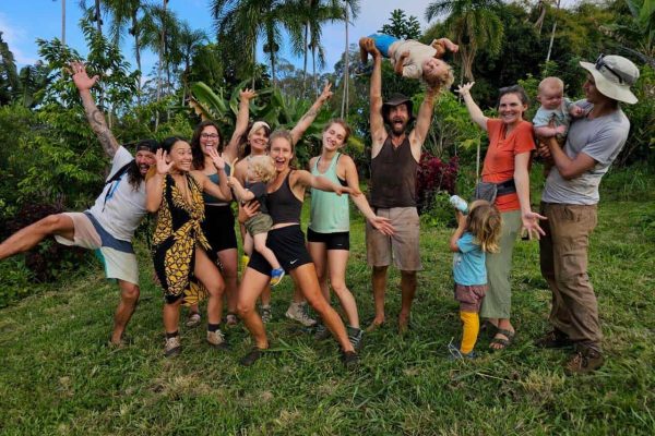 Volunteers celebrating a garden work day at Rainbow Bridge Hawaii, surrounded by tropical plants and palm trees